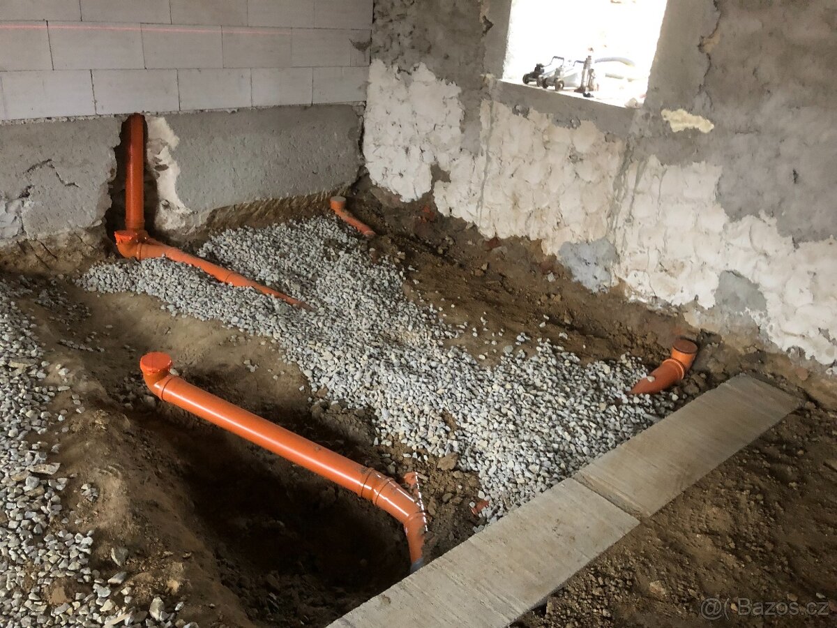 Pokládka oranžového kanalizačního potrubí ve výkopu se štěrkovým ložem